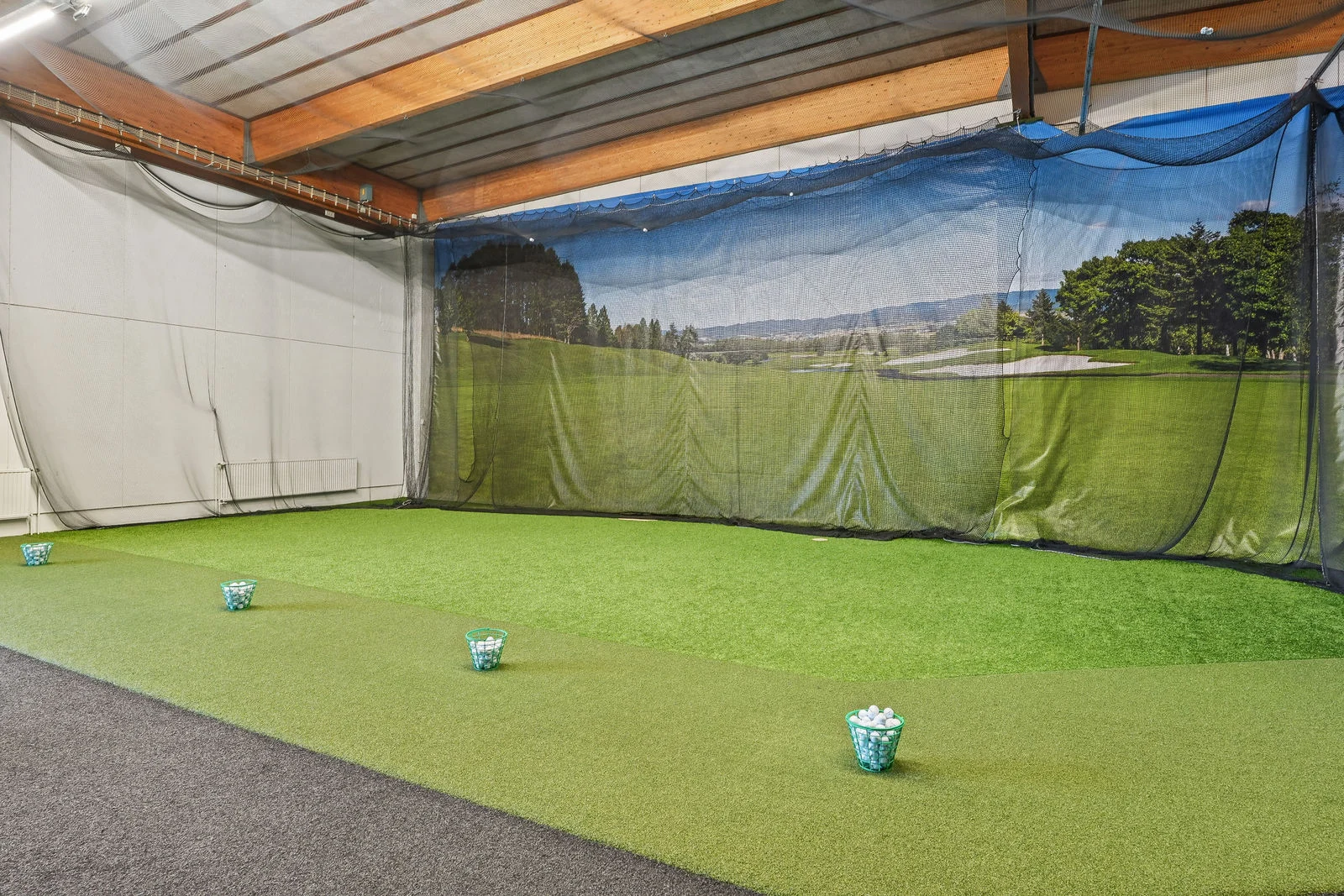Golfhallin harjoitusalue, jossa tekonurmi, harjoitusverkko ja palloja