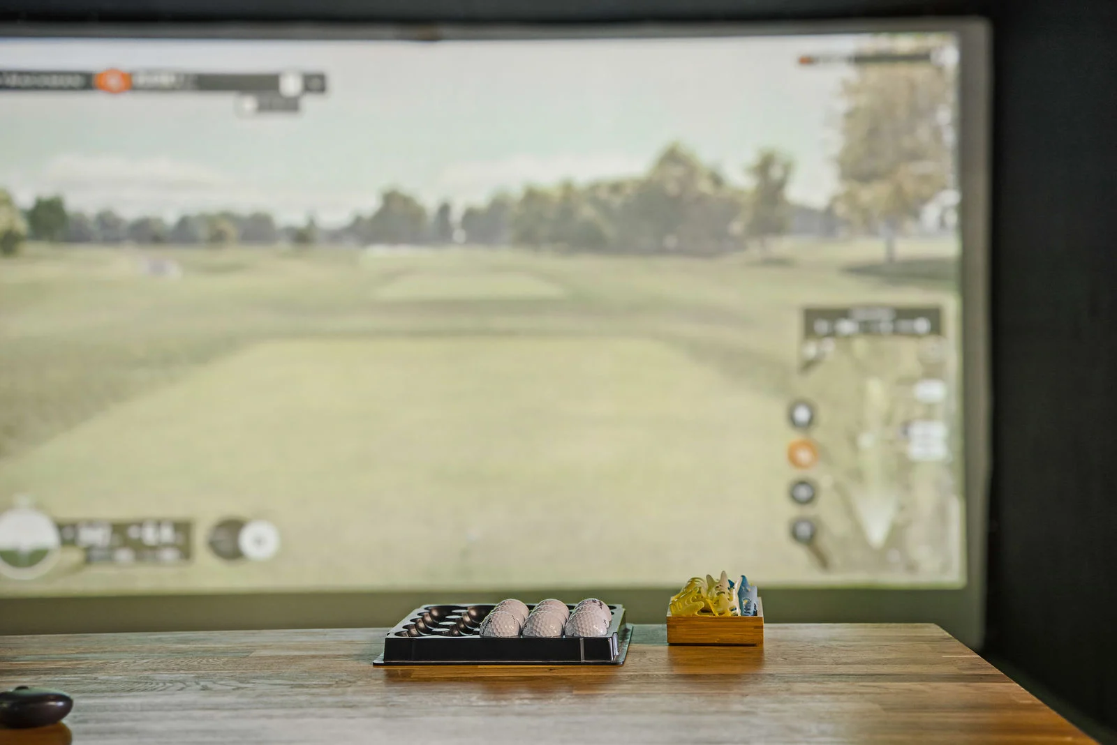 Simulaattorin kenttänäkymä ja golfpalloja pöydällä
